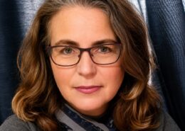 Professional headshot of Christian life coach minister wearing glasses and a gray sweater with a patterned scarf.