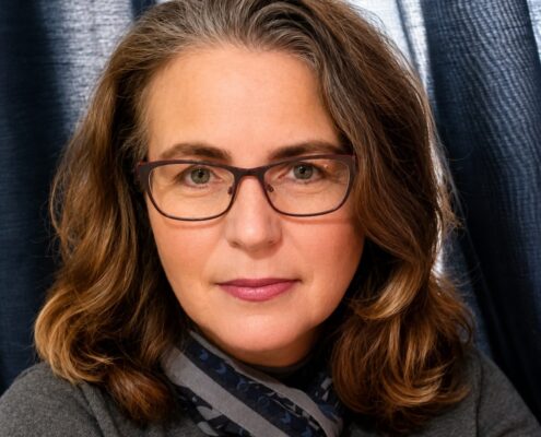 Professional headshot of Christian life coach minister wearing glasses and a gray sweater with a patterned scarf.