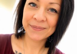 Professional headshot of Christian life coach minister Amberroysa wearing a cross necklace and burgundy top.