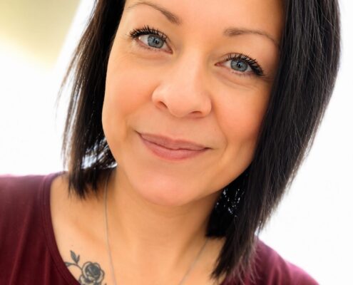 Professional headshot of Christian life coach minister Amberroysa wearing a cross necklace and burgundy top.