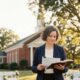 Female Christian wedding officiant holding an open Bible outdoors in Alabama while preparing to officiate a wedding ceremony.