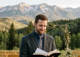 Male Christian wedding officiant standing in the Colorado Rocky Mountains holding an open Bible while preparing to lead a wedding ceremony, representing study-based ordination and Christian wedding ministry in Colorado.