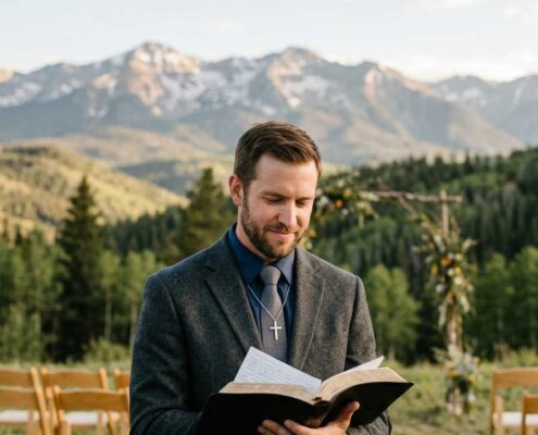 Male Christian wedding officiant standing in the Colorado Rocky Mountains holding an open Bible while preparing to lead a wedding ceremony, representing study-based ordination and Christian wedding ministry in Colorado.