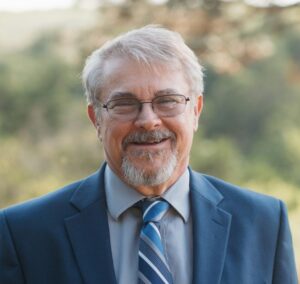 Christian wedding officiant and ministry leader standing outdoors in formal attire