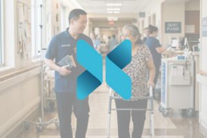 Hospital chaplain walking alongside an elderly woman using a walker in a hospital hallway, offering support and conversation.