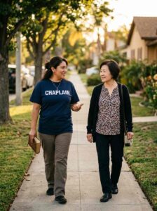Mexican female community chaplain walking beside a community member while holding a Bible and wearing a navy CHAPLAIN shirt