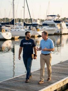 Male country club chaplain walking beside club member at marina holding Bible