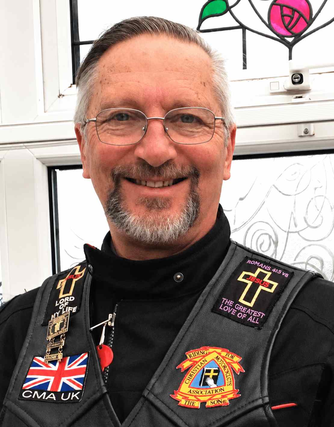 Motorcycle community chaplain wearing a Christian biker vest and smiling while serving bikers through faith-based encouragement and chaplain ministry.