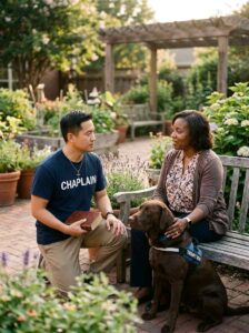 Male pet assisted chaplain speaking with woman beside therapy dog in peaceful garden