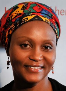 Professional headshot of Anne N., a Christian life coach minister, smiling while wearing a colorful patterned headscarf and earrings.