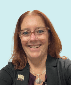 Professional headshot of Christine Kaiser, a Christian life coach and ministry leader, smiling while wearing business attire against a light blue background.