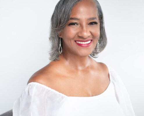 Professional headshot of Christian life coach minister Cynthia smiling in a white blouse against a light background.