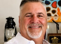 Professional headshot of Christian life coach minister Guy M smiling in a white dress shirt and cross necklace.