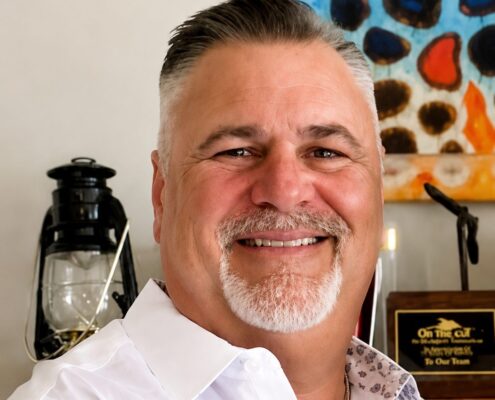 Professional headshot of Christian life coach minister Guy M smiling in a white dress shirt and cross necklace.