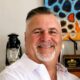 Professional headshot of Christian life coach minister Guy M smiling in a white dress shirt and cross necklace.