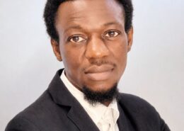 Professional headshot of Christian life coach minister Mwamba wearing a dark suit and white shirt with a calm, confident expression.