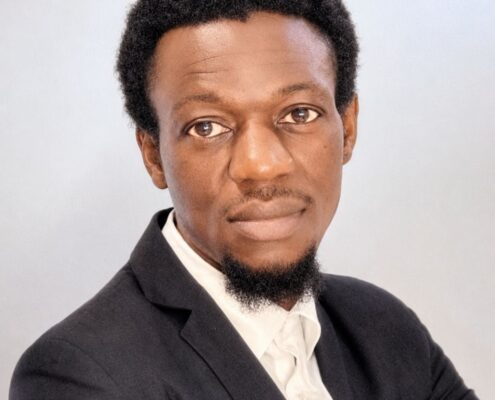 Professional headshot of Christian life coach minister Mwamba wearing a dark suit and white shirt with a calm, confident expression.