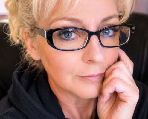 Portrait of Christian life coach minister Nicholle S. wearing black glasses and a black top, smiling gently in a professional headshot.