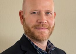 Portrait of Christian life coach minister Tim Ketchum wearing a navy blazer and collared shirt against a neutral background.