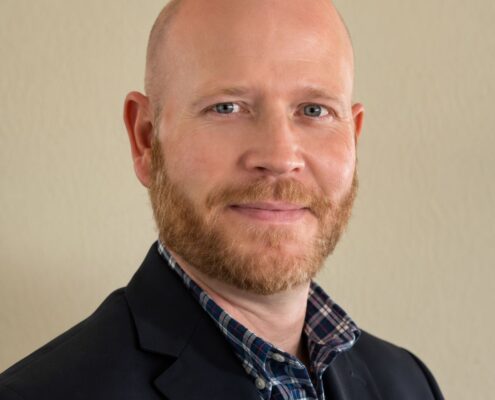 Portrait of Christian life coach minister Tim Ketchum wearing a navy blazer and collared shirt against a neutral background.
